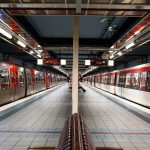 Modern subway station in Hamburg with red trains and tiled platform under bright lights.