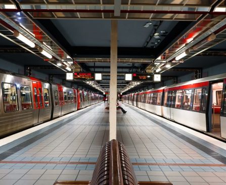Modern subway station in Hamburg with red trains and tiled platform under bright lights.