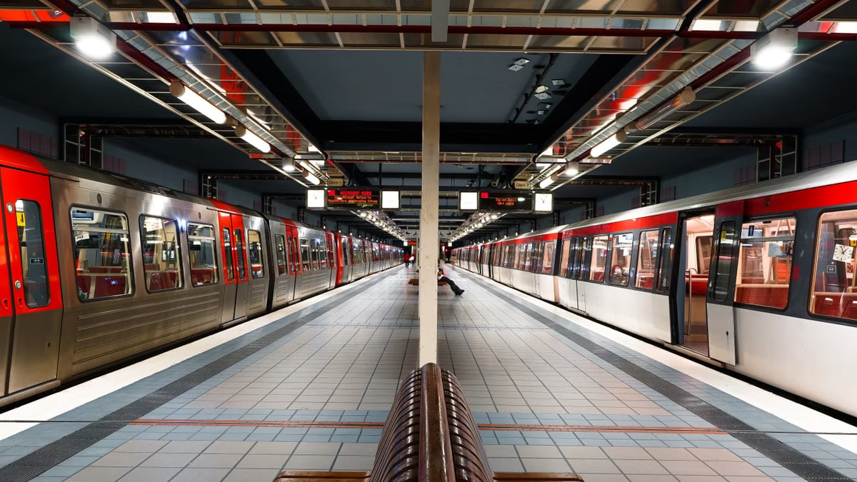 Modern subway station in Hamburg with red trains and tiled platform under bright lights.